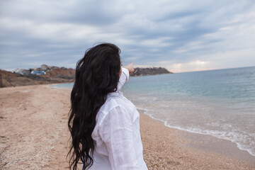 Obraz premium beautiful plus size woman with long haiws walking in the beach against the sea.. The overweight model wearing style shirt and and bikini