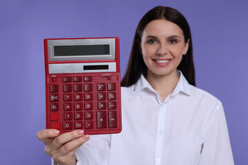 Smiling accountant against purple background, focus on calculator