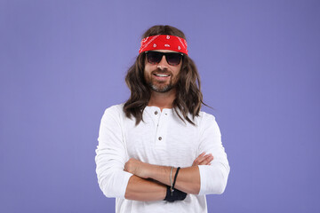 Stylish hippie man in sunglasses on violet background