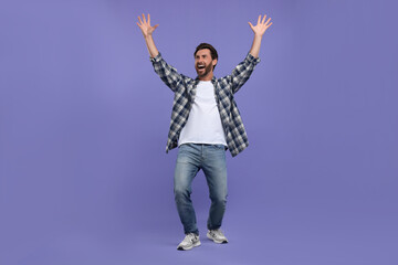 Emotional sports fan celebrating on purple background