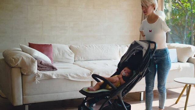 Woman with amputee arms pushing baby stroller in living room