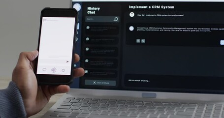 Video of biracial businessman using smartphone with copy space and laptop with ai chat on screen - Powered by Adobe