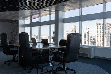 Table and chairs in the interior of a modern office with large panoramic windows against the...