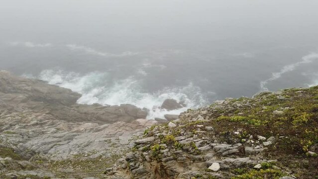 wave from a cliff at pointe du raz in brittany, seen from above. in the mist. video in 4k.