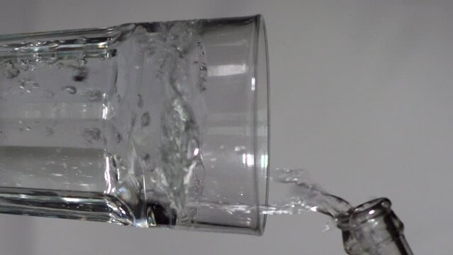 Pouring Water Into a Drinking Glass on a Grey Studio Background - Vertical 
