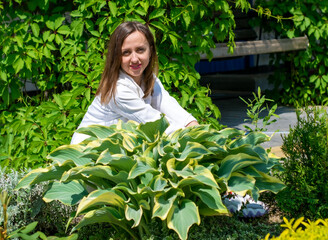 A woman sits by a large Kali bush in the afternoon.