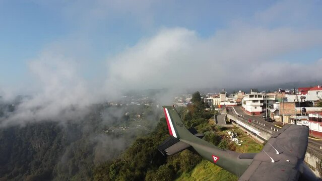 The Cessna 252S model plane from the Mexican Air Force placed for tourist attraction with the rear towards the ravines of Zacatlan, Cityscape in the atmospheric cloud, Puebla, Mexico