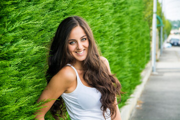 Photo of a woman posing in front of a vibrant green bush