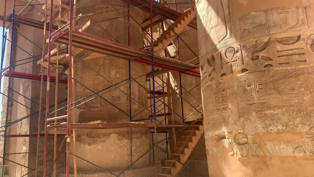 Karnac temple scaffolding and stairs around ancient columns to restore and preserve monument.  Pan up, sunny day.