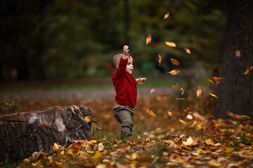 Cute little baby boy playing and having fun in autumn park with yellow leaves