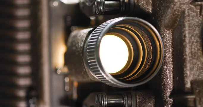 Macro close up of an old vintage analog 8mm projector light bulb playing an 8mm film reel