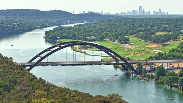 Hyper-Lapse of iconic Penny Backer Bridge in Austin. Moving Southeast towards the downtown Austin skyline. A barge carrying a crane being delivered to the boat ramp; several boats moving about.