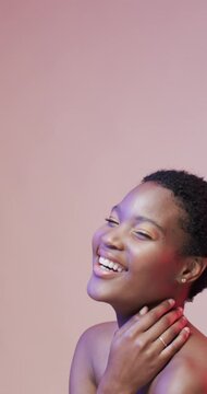 Vertical video of happy african american woman with dark hair in blue and pink light, slow motion