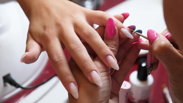 From above of crop unrecognizable manicurist doing nail art for female client in beauty salon