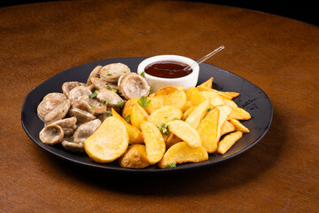 portion of finger food with bratwurst bratwurst fried sausages and potatoes and barbecue sauce on wooden table