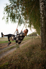 a beautiful girl swings on a swing in the middle of an autumn birch forest. autumn atmosphere in the forest