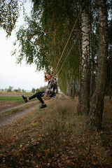 a beautiful girl swings on a swing in the middle of an autumn birch forest. autumn atmosphere in the forest