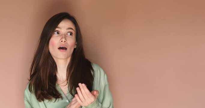 Pretentious brunette straight hair woman in green shirt clapping, and looking annoyed over beige background. Girl applauds with a grin, sarcasm sarcastically clapping her hands.