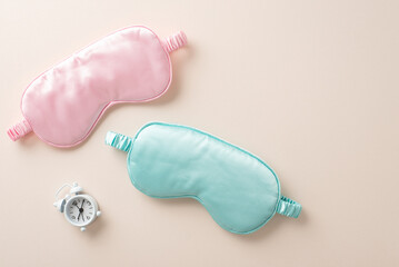 Healthy nighttime sleep concept. High-angle view photograph of pink and blue sleep mask and alarm...
