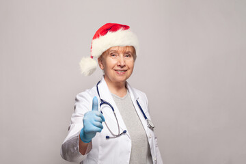 Portrait of Christmas doctor or nurse Santa with thumb up on white background