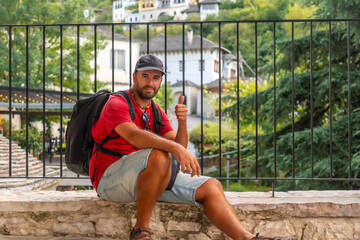 Portrait of a smiling tourist sitting resting on a viewpoint the city of Gjirokaster or Gjirokastra. Albanian