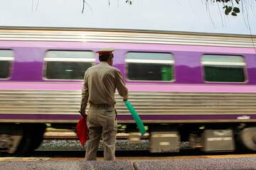 man with flag standing on platform at train station.