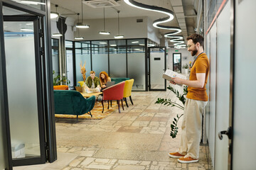 bearded team lead with documents near team talking in modern coworking environment