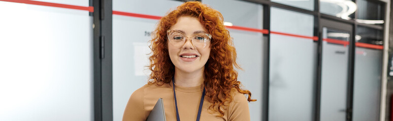 Obraz premium professional headshot, joyful redhead team lead, businesswoman looking at camera in office, banner
