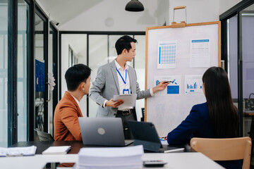 Group of young Asian business people discussing business plan at modern startup in creative business discussing work modern office building.
