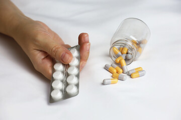 Pills in a palm of female hand on the bed. Concept of medication, vitamins or sleeping pill