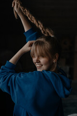 A young girl in a blue hoodie is messing with her braids on the eve of the new year