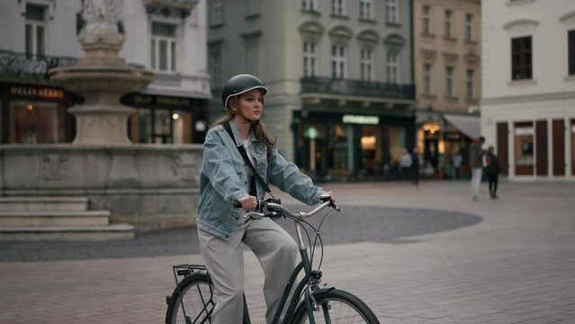 Slow motion view of happy beautiful young woman riding bicycle on street outdoor near building city