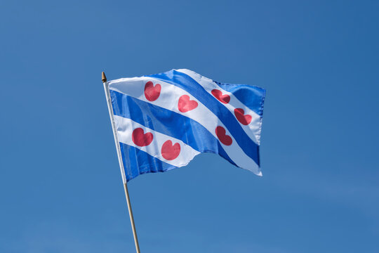 Small Frisian flag waving in the wind in front of a deep blue sky.