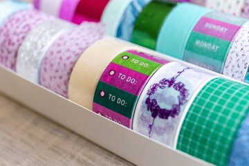 A box full of colorful rolls of washi tape having different colors, textures and patterns on a...