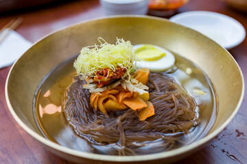 Delicious bowl of fresh Mul Naengmyeon, also called Pyongyang noodles: dish of North Korean origin which consists of long and thin handmade noodles,  served with a spicy dressing