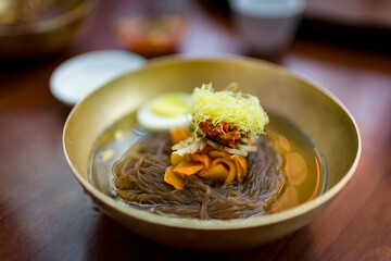Delicious bowl of fresh Mul Naengmyeon, also called Pyongyang noodles: dish of North Korean origin which consists of long and thin handmade noodles,  served with a spicy dressing