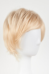 Natural looking blonde fair wig on white mannequin head. Short hair cut on the plastic wig holder isolated on white background.