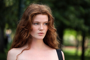 Portrait of ginger girl with long red hair and freckles in summer park. Young sensual model,...