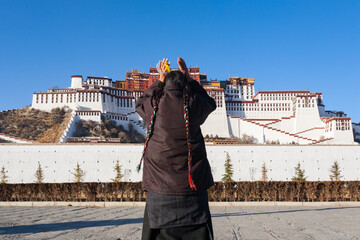 LHASA, TIBET - CHINA: unidentified Tibetan female pilgrim with long braided hair prays in front of the Potala palace