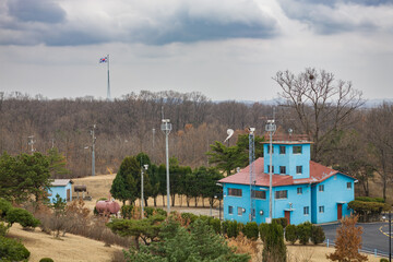 PANUMJUOM, NORTH KOREA: blue South Korean guard post with surveillance cameras and giant pole with South Korean flag of Taesong village in the background