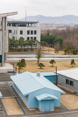 PANUMJUOM, NORTH KOREA: blue Military Armistice Commission (MAC) building, Peace House in the center and Kijong village giant pole with North Korean flag in the background