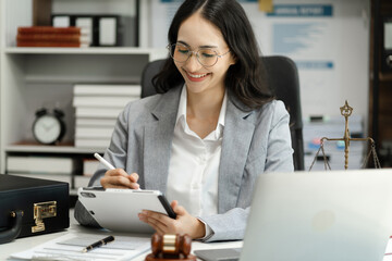 Fototapeta premium Female Legal counsel working with paperwork on his desk in office workplace working with tablet computer. Justice and law concept.