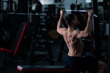 A man does a chest pulldown in the gym.