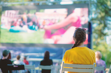People sit in a summer open-air cinema.