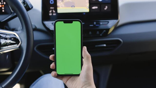Close up of a man's hand holding a mobile telephone with a vertical green screen in car chroma key smartphone technology cell phone street touch message display hand