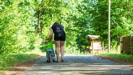 Eine Mutter bringt ihrem kleinen Sohn das Fahrrad fahren bei