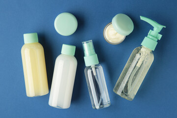 Travel cosmetic bottles on dark blue background. Minimalist bodycare beauty products for vacation or journey. Top view. Copyspace.