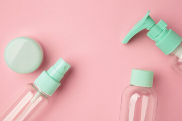 Empty travel cosmetic bottles on pink background. Minimalist bodycare beauty products for vacation or journey. Top view. Copyspace.