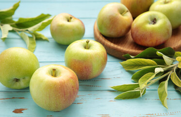 Ripe green apples with green leaves on blue wooden background