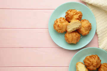 Homemade profiteroles with cream on plate on pink background. Fresh baked golden profiterole. Space for text
